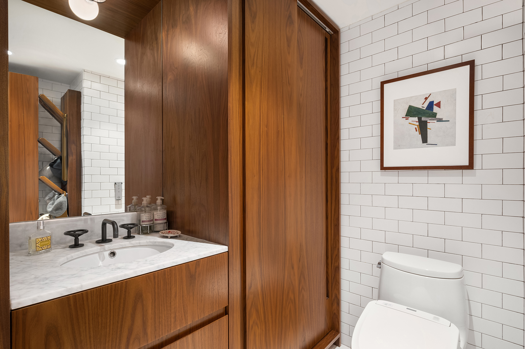 235 East 55th Street, Unit 44B Manhattan, NY 10022 - Photo 9 of 12 a bathroom with a toilet sink vanity and mirror