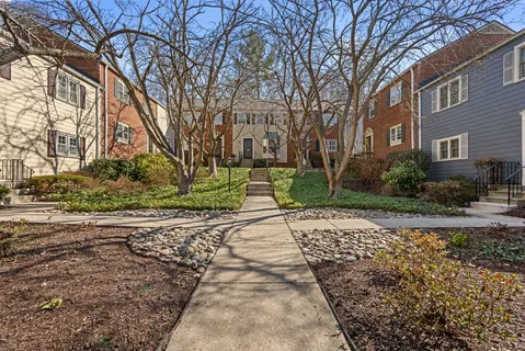 a pathway of a house with a yard and trees