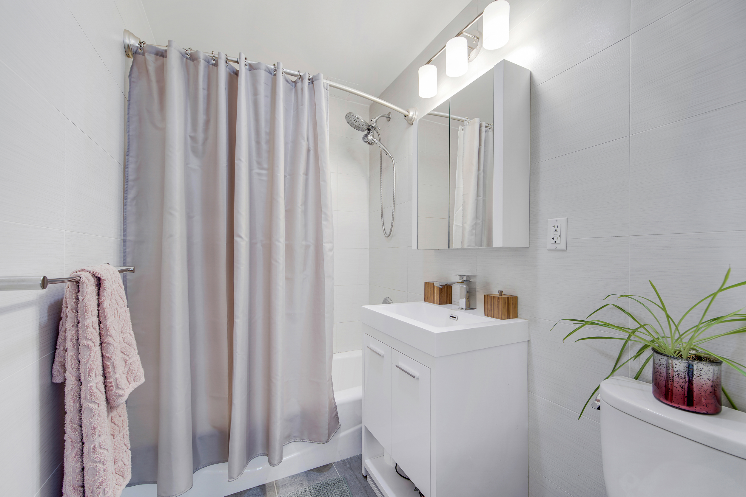 27-34 27th Street, Unit 1B Queens, NY 11102 - Photo 8 of 10 a bathroom with a sink a mirror and a shower curtain