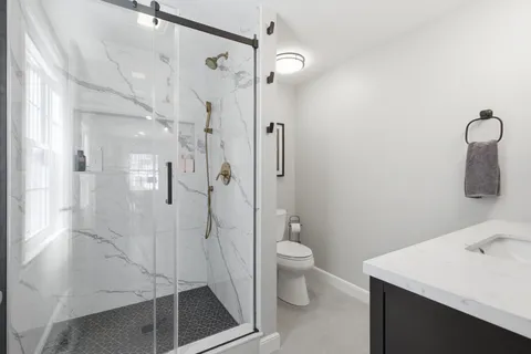 a bathroom with a sink a toilet and shower