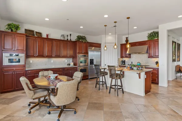 a kitchen with stainless steel appliances granite countertop a stove top oven a sink dishwasher a dining table and chairs with wooden floor