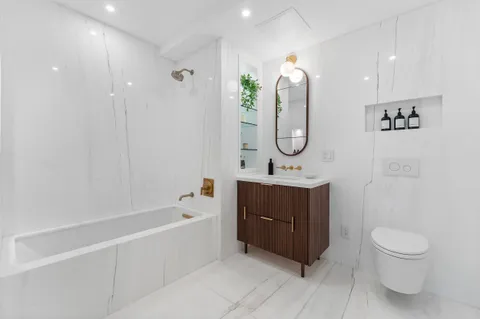 a spacious bathroom with a tub sink toilet and mirror