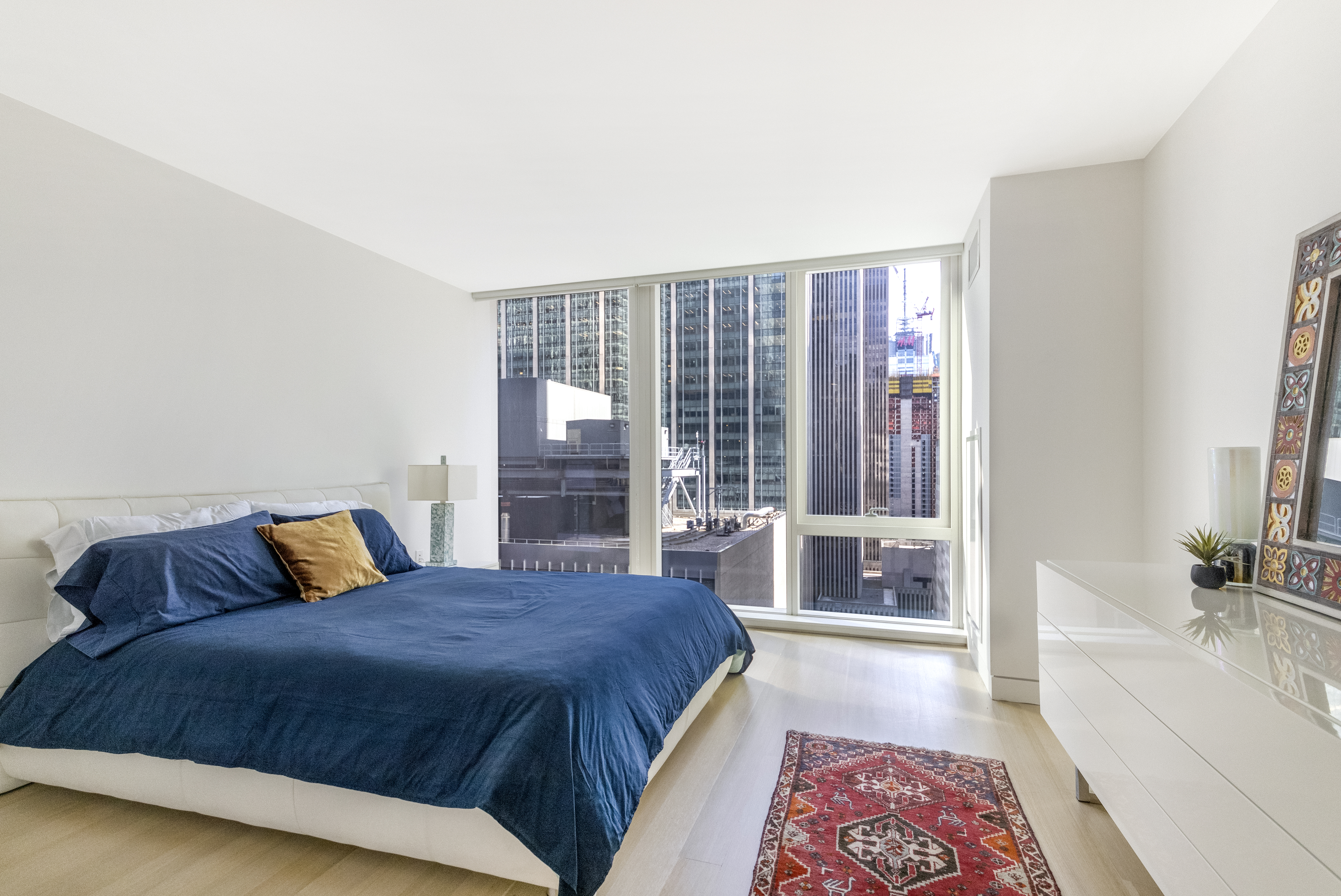 135 West 52nd Street, Unit 23C Manhattan, NY 10019 - Photo 9 of 19 a bedroom with a large bed and a couch