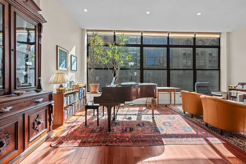 a living room with furniture large window and wooden floor