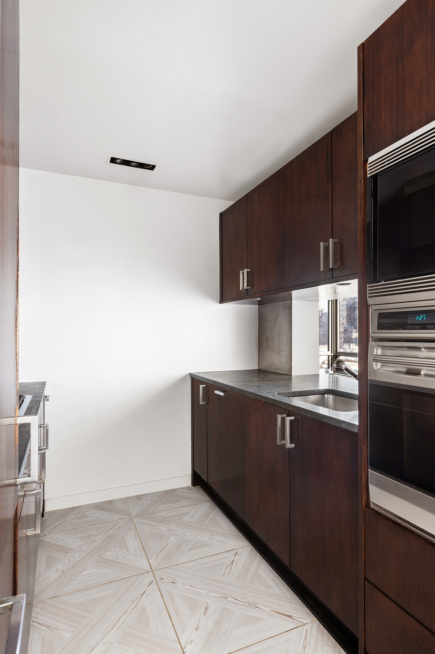 450 East 83rd Street, Unit 8B Manhattan, NY 10028 - Photo 13 of 22 a kitchen with granite countertop a sink cabinets and stainless steel appliances