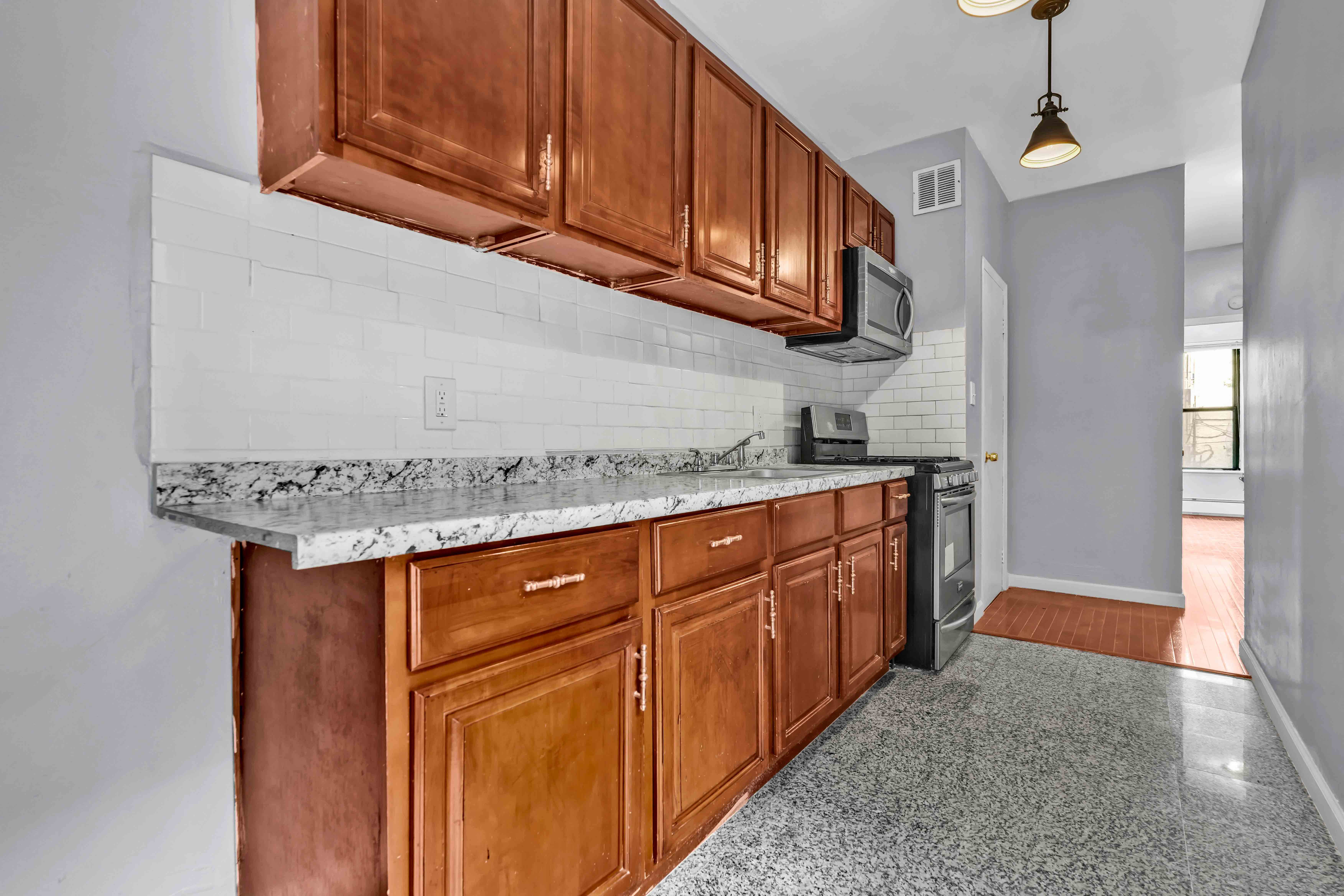 1633 St Johns Place, Unit 3 Brooklyn, NY 11233 - Photo 22 of 29 a kitchen with granite countertop wooden cabinets and a stainless steel appliances