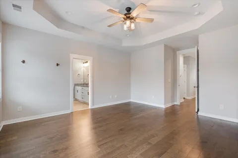 an empty room with wooden floor and a ceiling fan