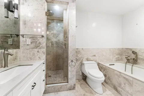 a bathroom with a bathtub shower sink vanity and toilet