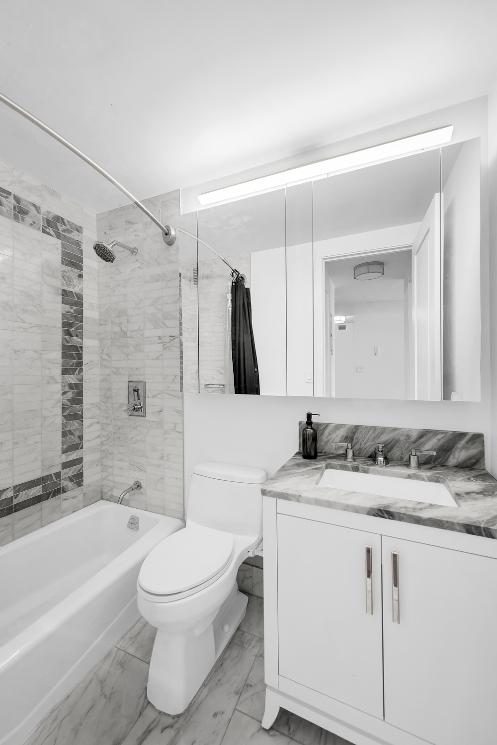 200 East 94th Street, Unit 1412 Manhattan, NY 10128 - Photo 6 of 15 a bathroom with a granite countertop sink toilet a mirror and bathtub