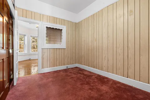 a view of a hallway with wooden floor and livingroom with fireplace