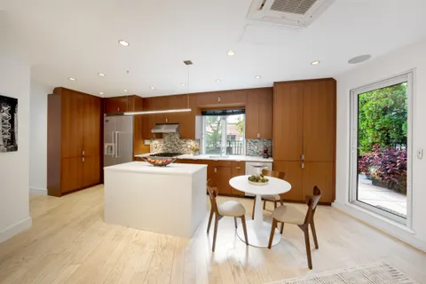 a kitchen with stainless steel appliances granite countertop a table chairs and a refrigerator