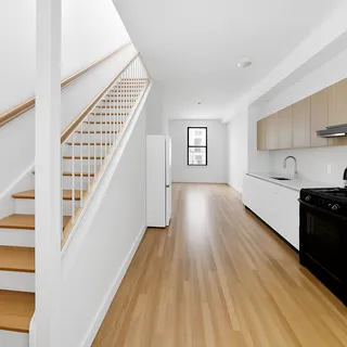 a view of a kitchen with wooden floor electronic appliances and stairs