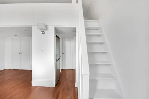 a view of a hallway with wooden floor and closet
