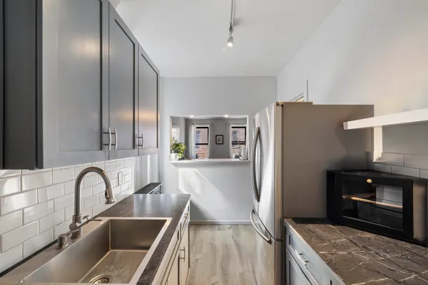 a kitchen with stainless steel appliances granite countertop a refrigerator a stove and a sink with wooden floor