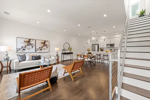 a living room with furniture and kitchen view with wooden floor