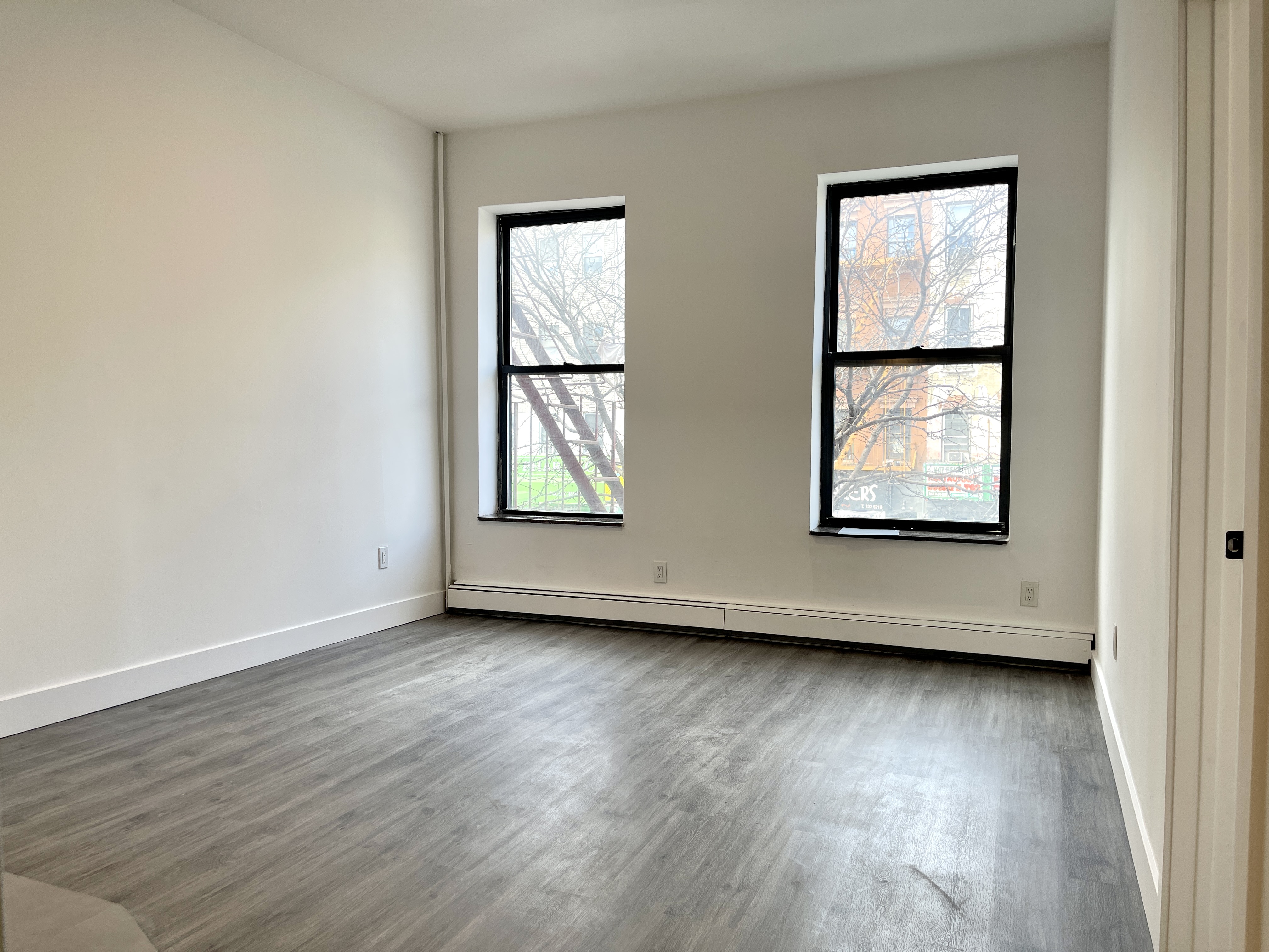 1999 3rd Avenue, Unit 1 Manhattan, NY 10029 - Photo 4 of 23 an empty room with wooden floor and windows