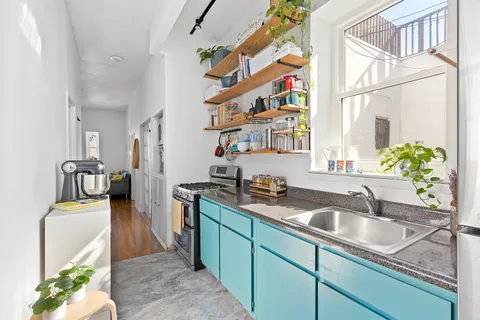 a kitchen that has a sink and a stove with wooden floor