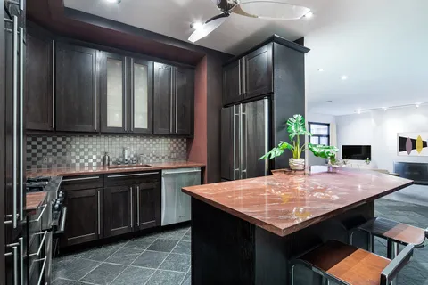a kitchen with kitchen island stainless steel appliances a sink cabinets and wooden floor