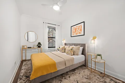 a bedroom with a bed a mirror and a lamp on dresser