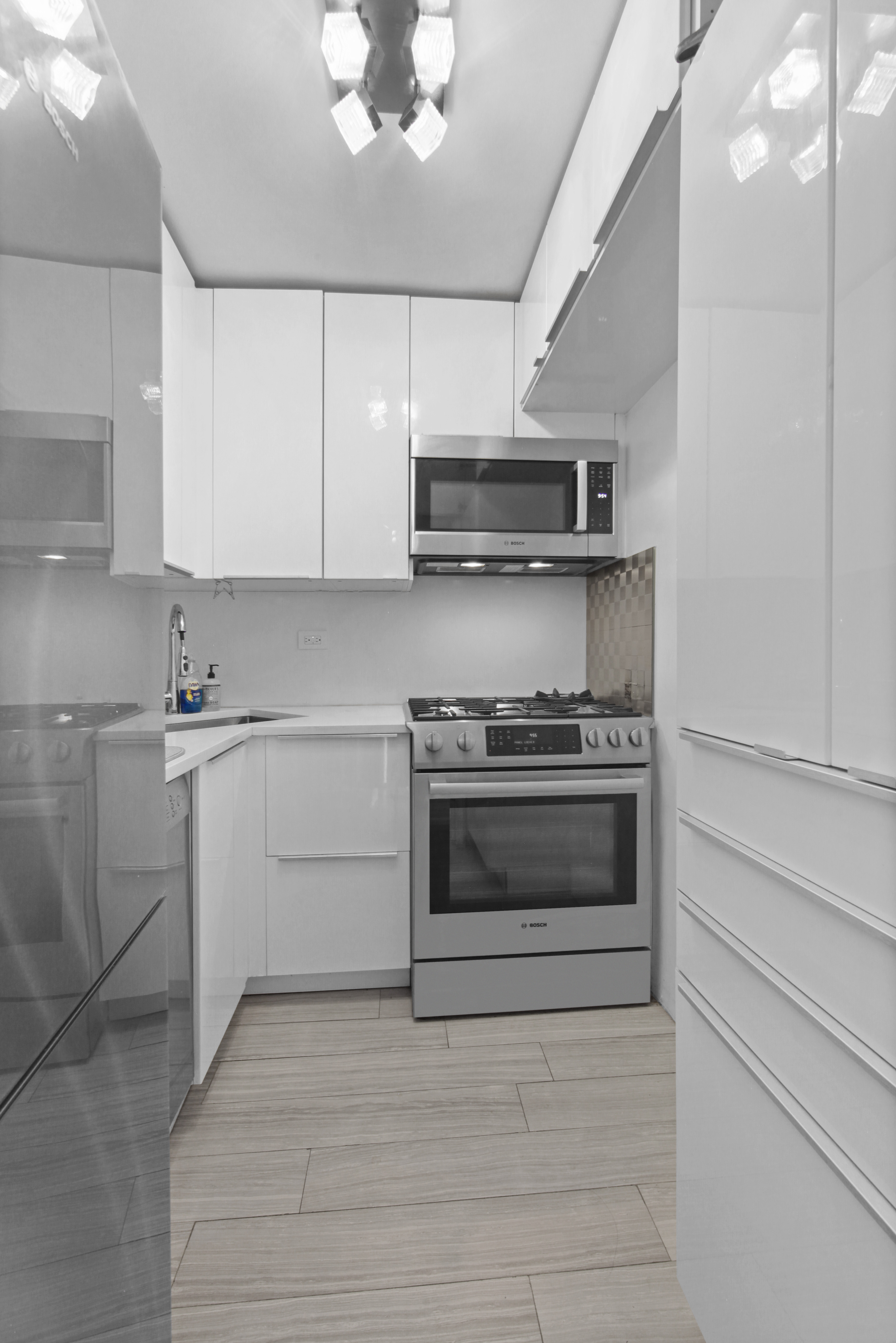 220 East 60th Street, Unit 5F Manhattan, NY 10022 - Photo 5 of 8 a kitchen with stainless steel appliances white cabinets and a stove top oven