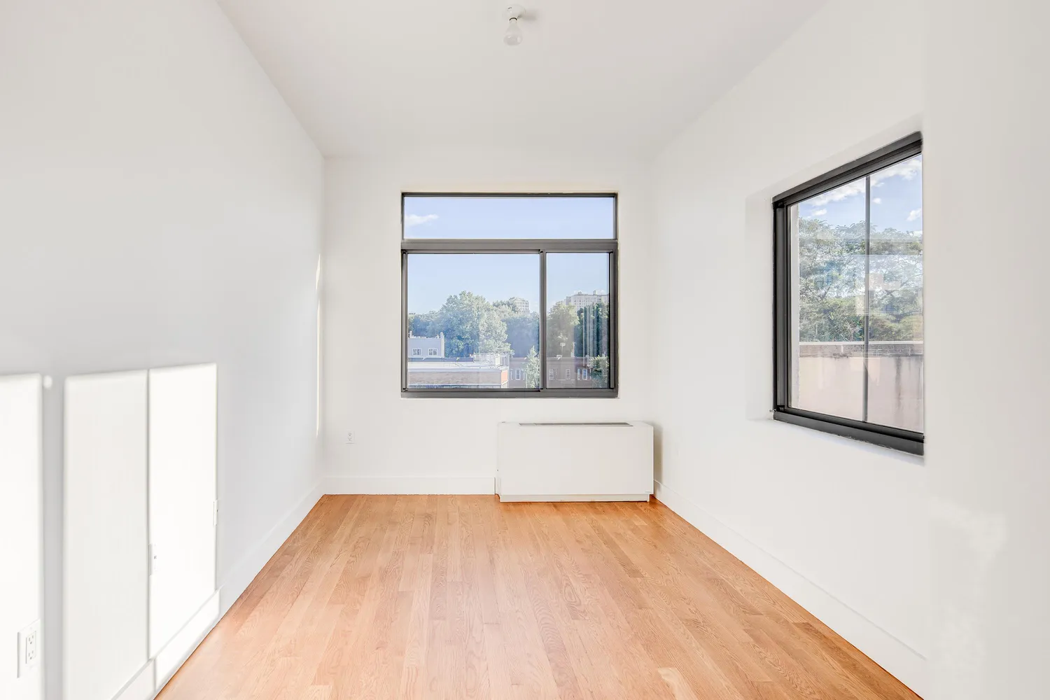 a view of an empty room with wooden floor and a window