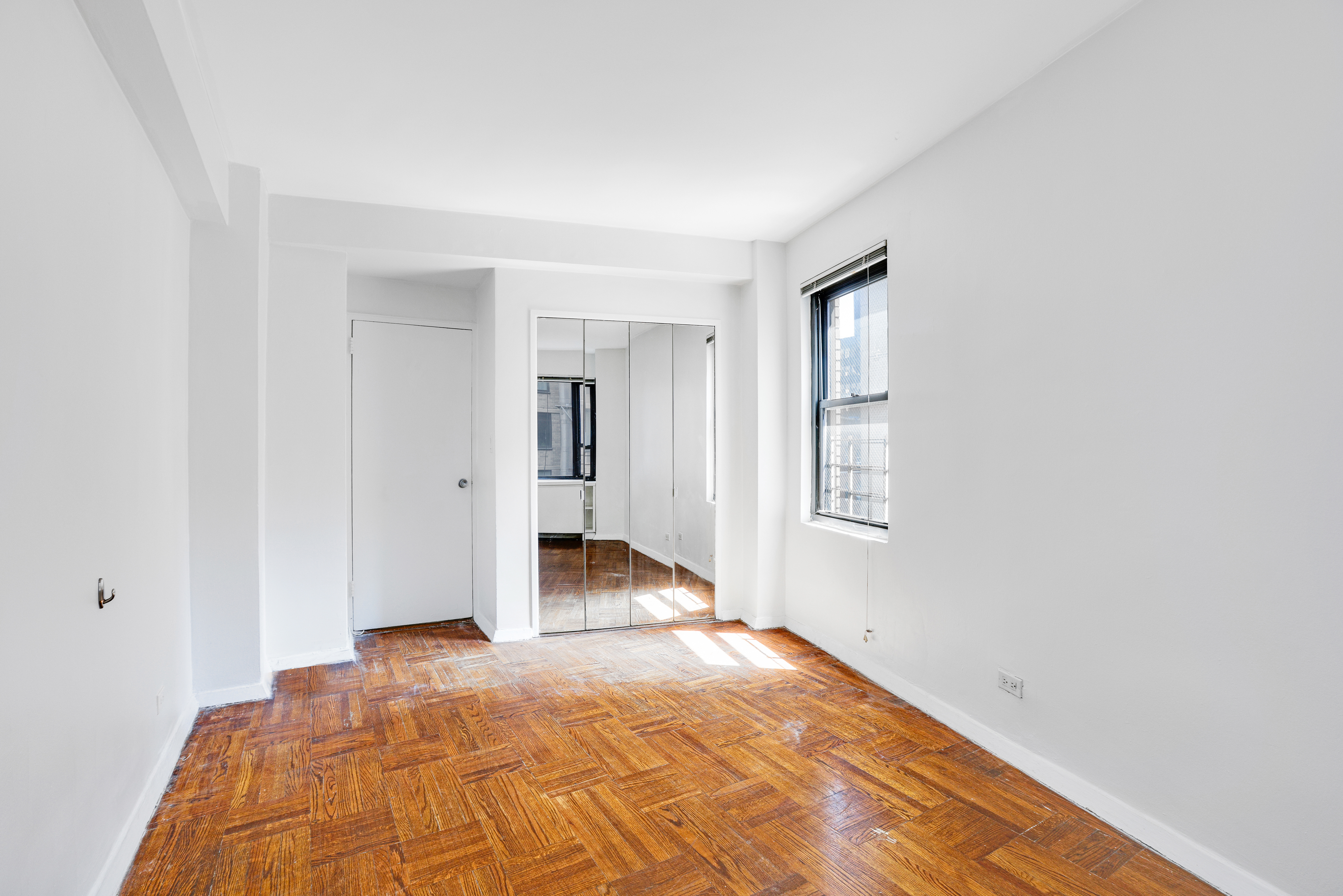 210 East 47th Street, Unit 7J Manhattan, NY 10017 - Photo 9 of 12 a view of a bedroom with wooden floor and bathroom