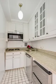 a kitchen with stainless steel appliances granite countertop a sink dishwasher stove and white cabinets