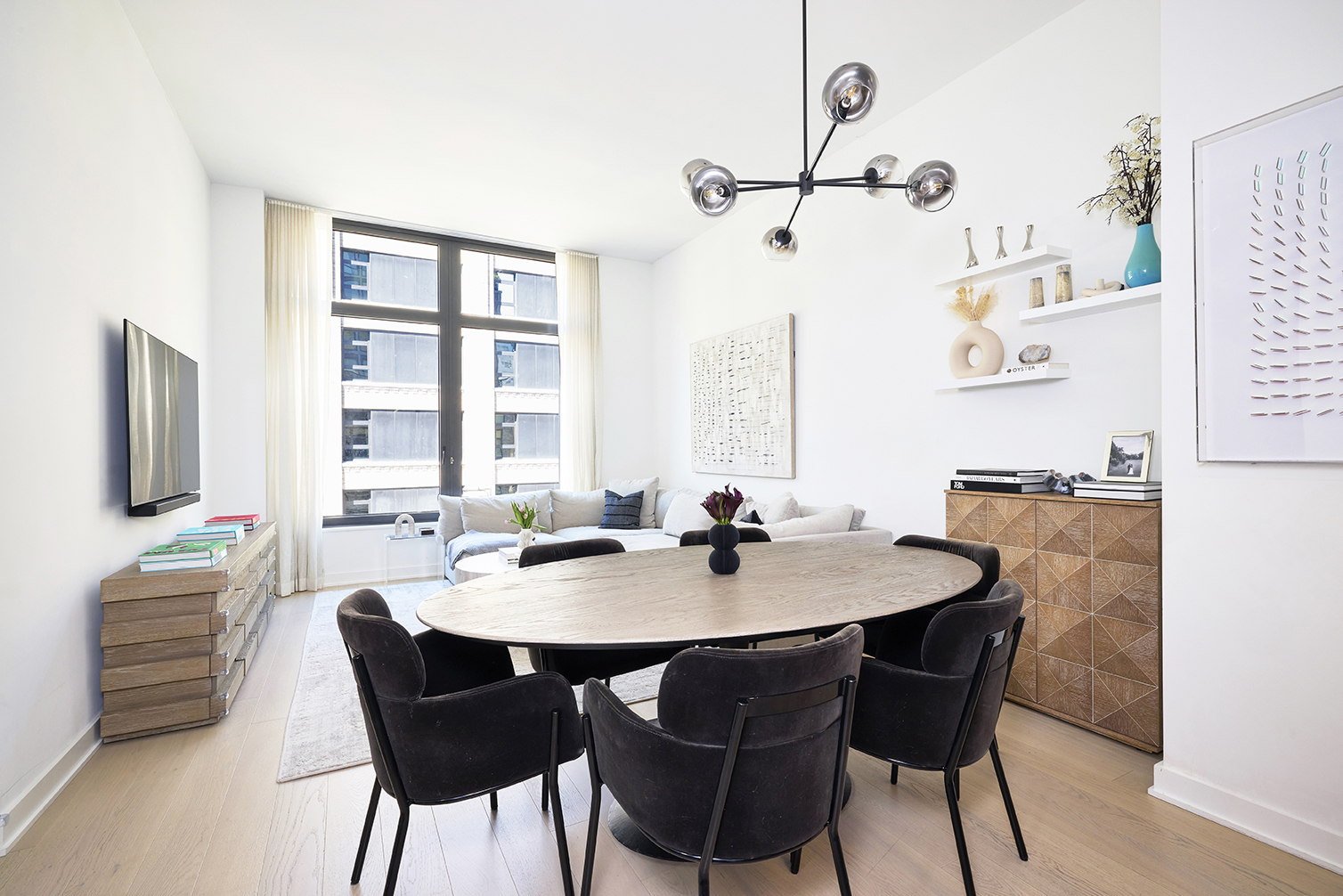 a view of a dining room and livingroom with furniture wooden floor a rug and a chandelier