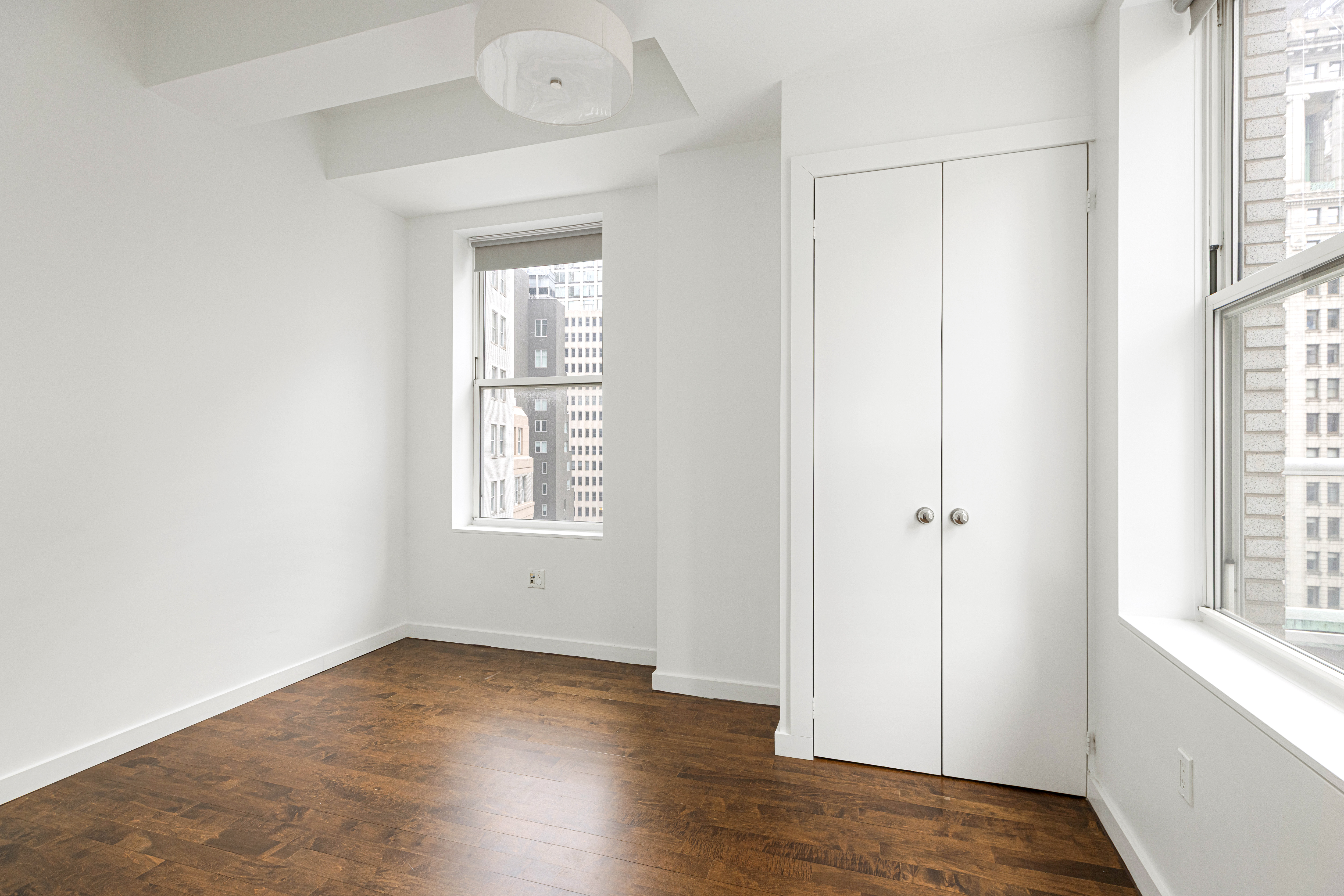 15 Broad Street, Unit 2300 Manhattan, NY 10005 - Photo 14 of 36 an empty room with wooden floor and windows