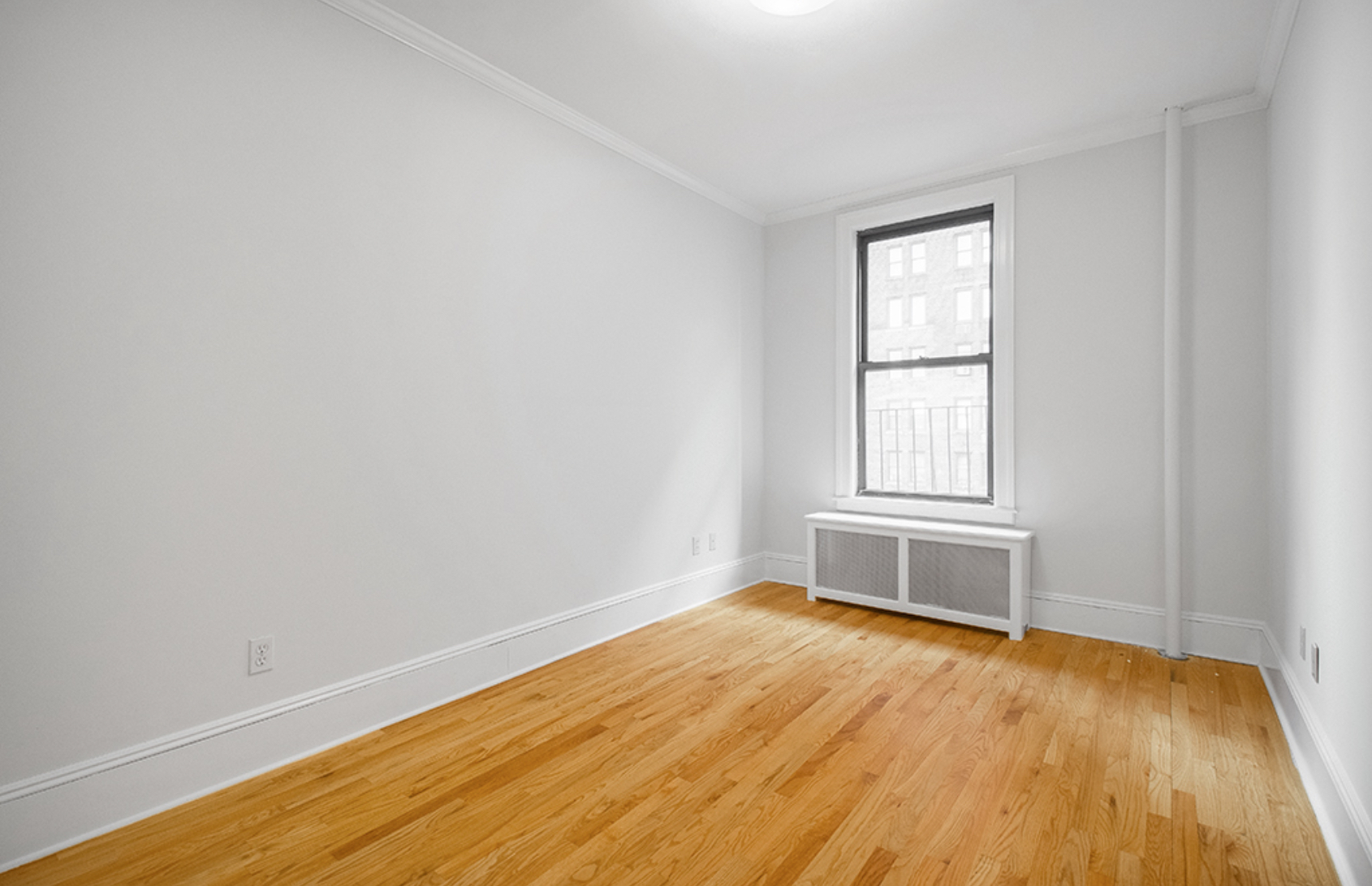 1240 Park Avenue, Unit 3B Manhattan, NY 10128 - Photo 6 of 12 an empty room with wooden floor and windows