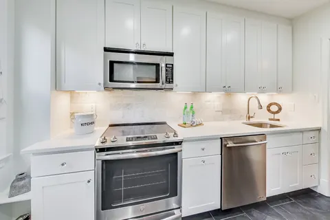 a kitchen with white cabinets and stainless steel appliances