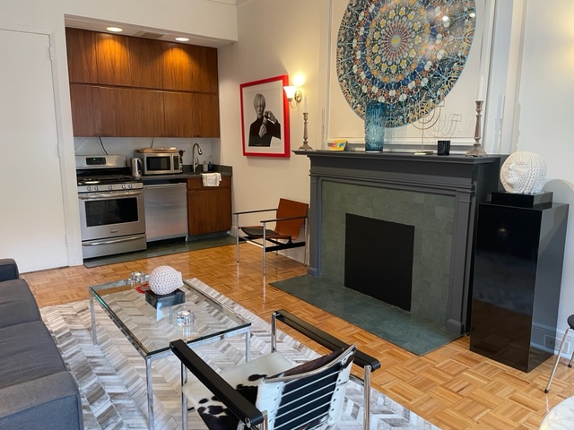 128 East 62nd Street, Unit 4F Manhattan, NY 10065 - Photo 4 of 9 a living room with furniture a flat screen tv and kitchen view
