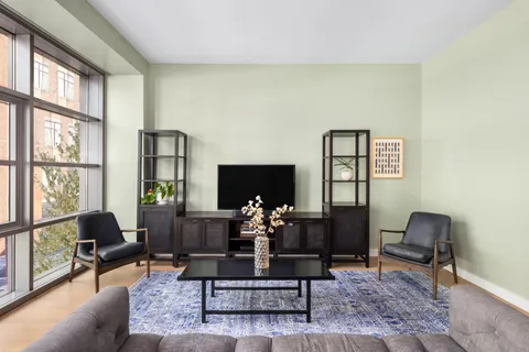 a living room with couches coffee table and a flat screen tv with wooden floor
