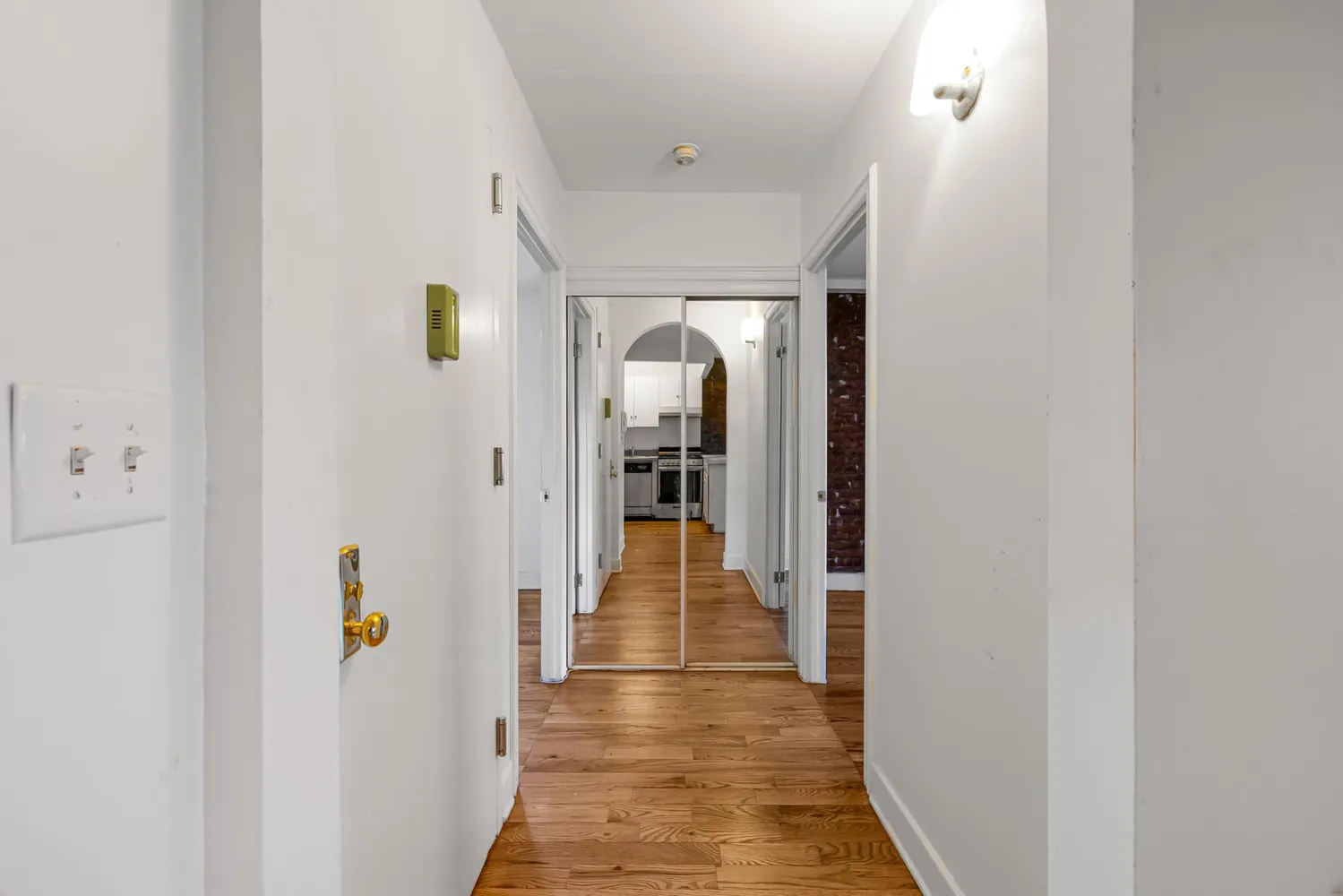a view of a hallway with wooden floor and a living room