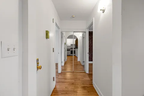 a view of a hallway with wooden floor and a living room