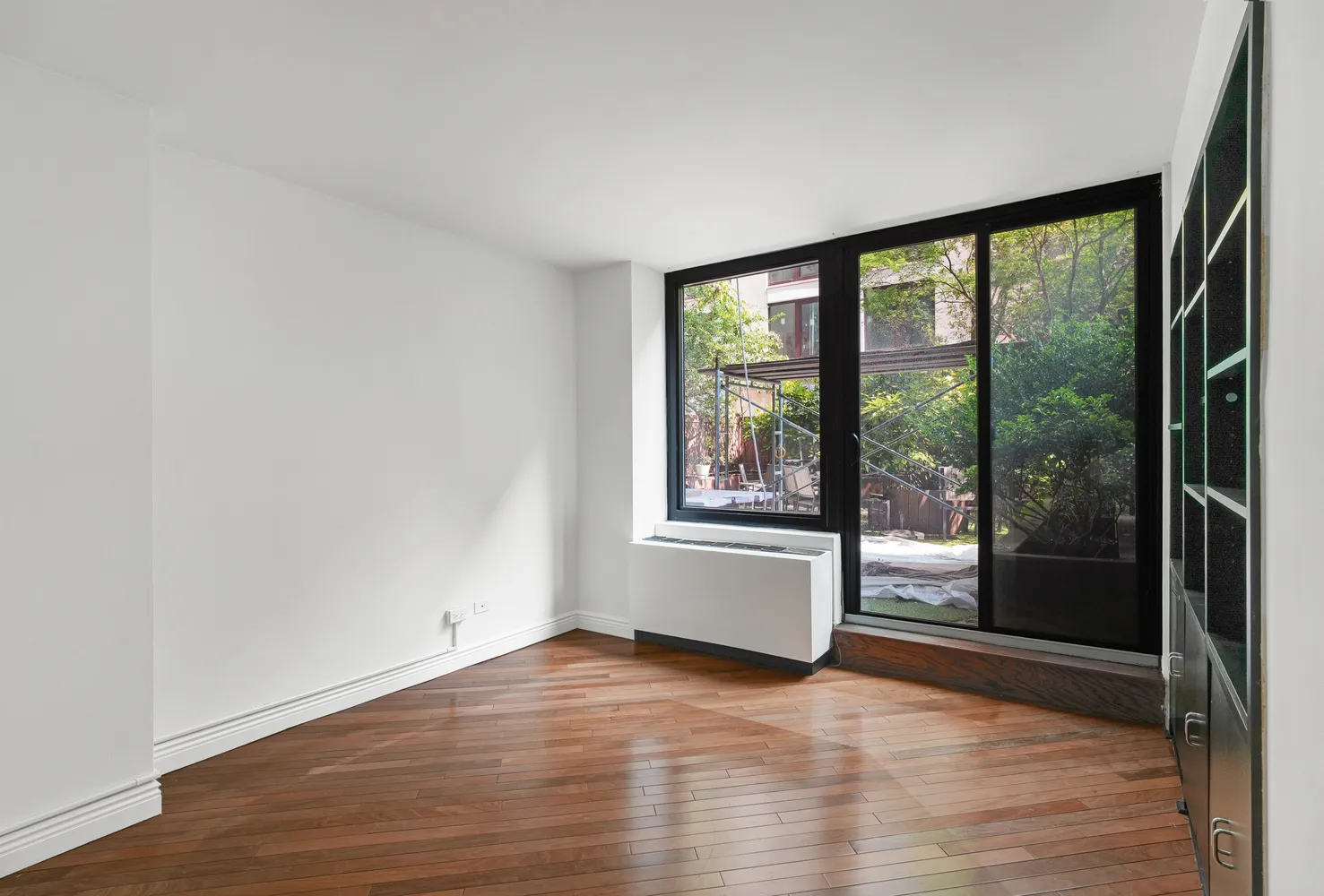 a view of empty room with wooden floor and floor to ceiling window