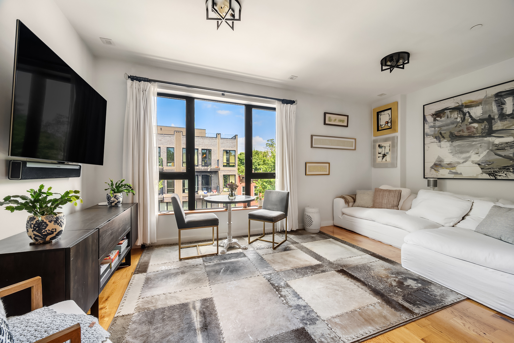 a living room with furniture flat screen tv and large windows