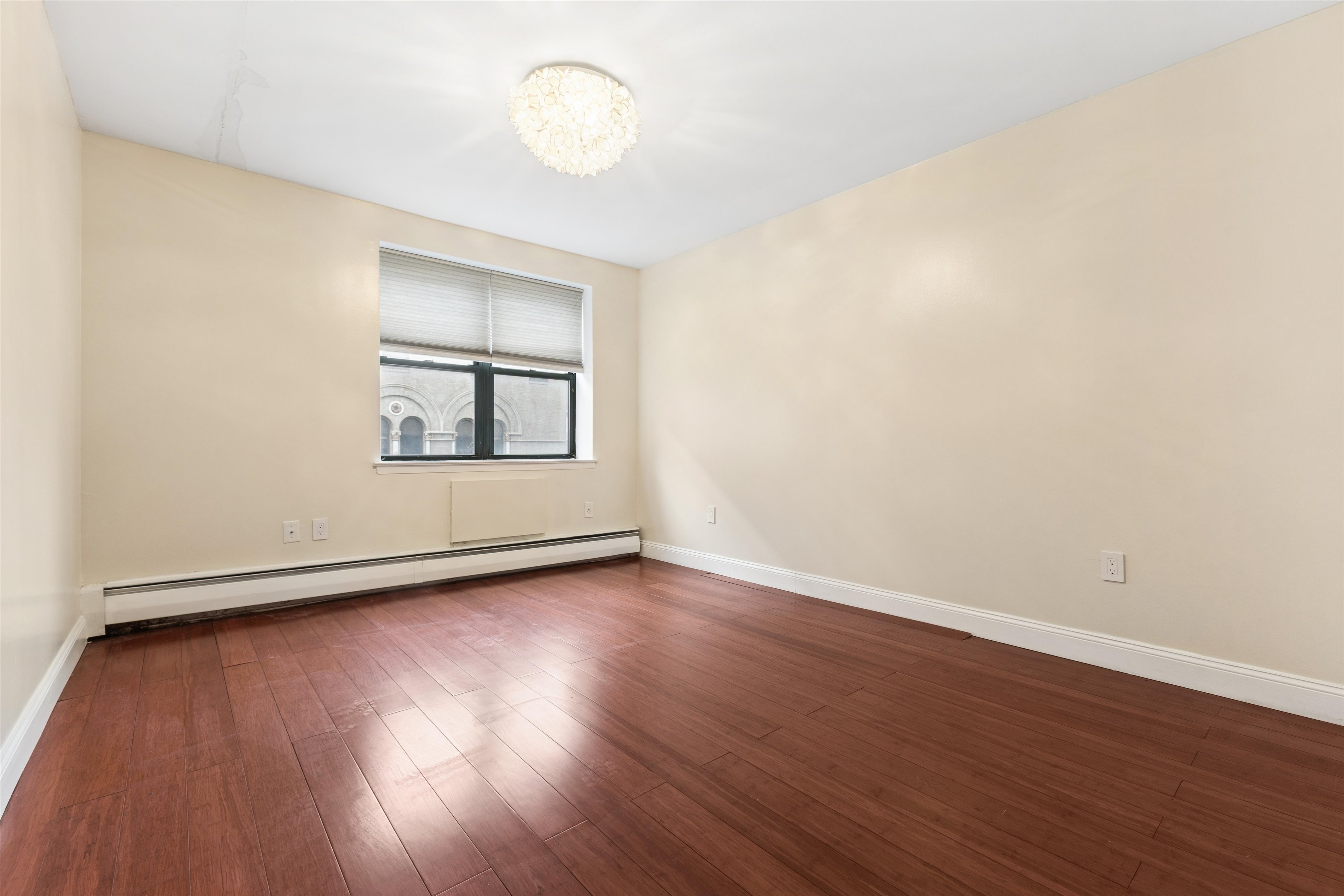 1919 Madison Avenue, Unit 418 Manhattan, NY 10035 - Photo 9 of 16 an empty room with wooden floor and windows