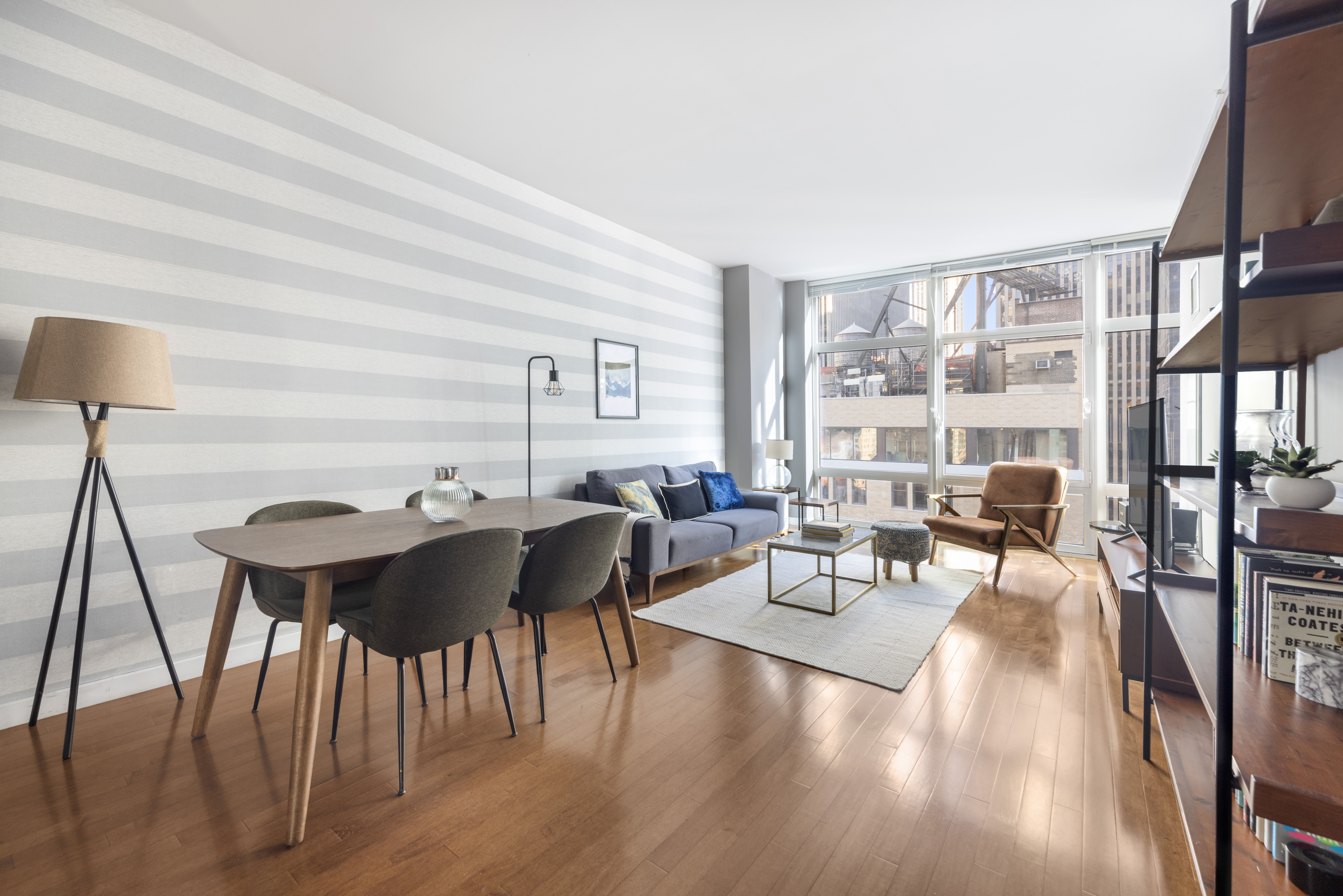 a living room with furniture a rug potted plant and a large window
