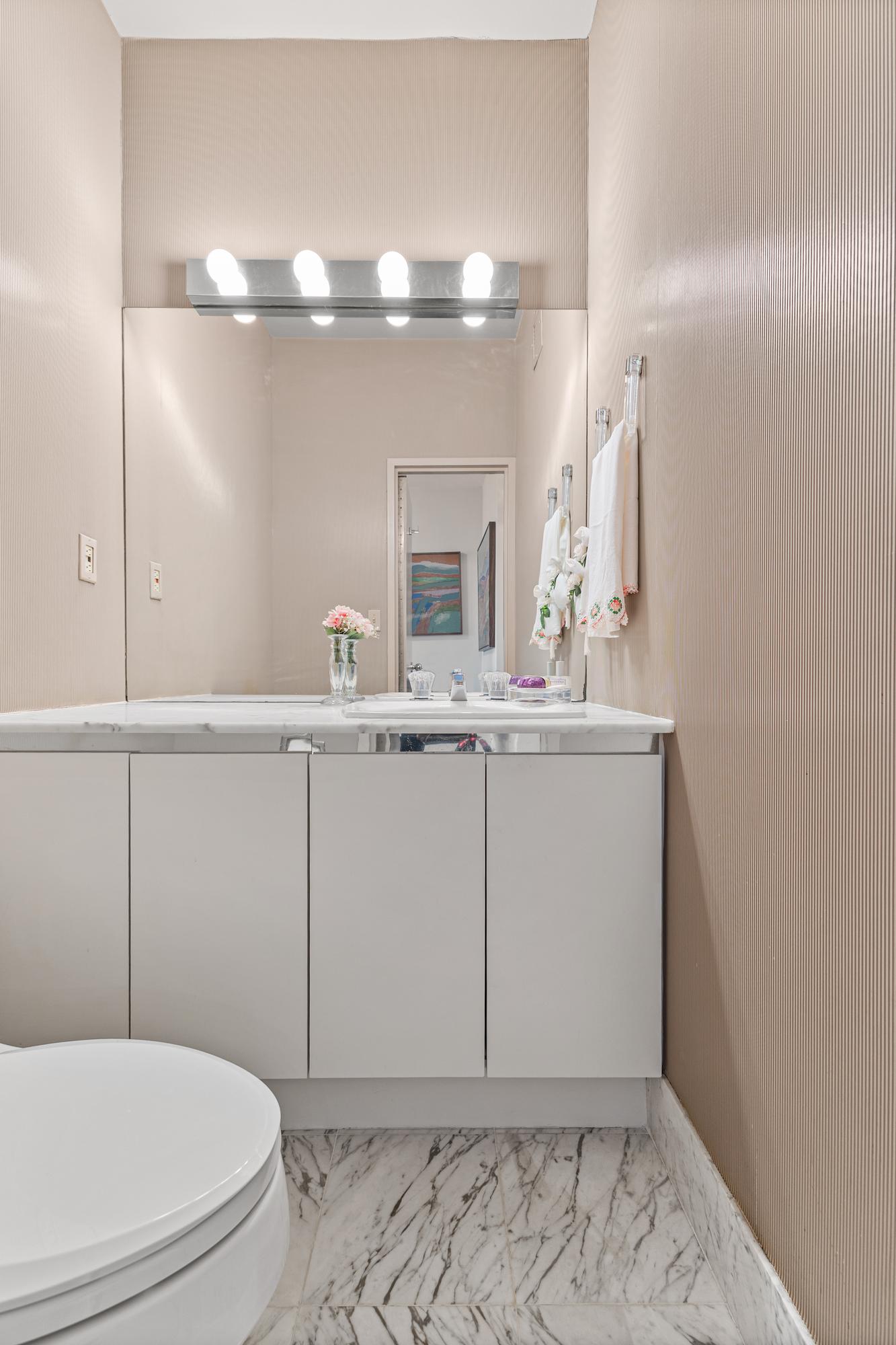 167 East 61st Street, Unit 20E Manhattan, NY 10065 - Photo 14 of 24 a bathroom with a sink a toilet and mirror