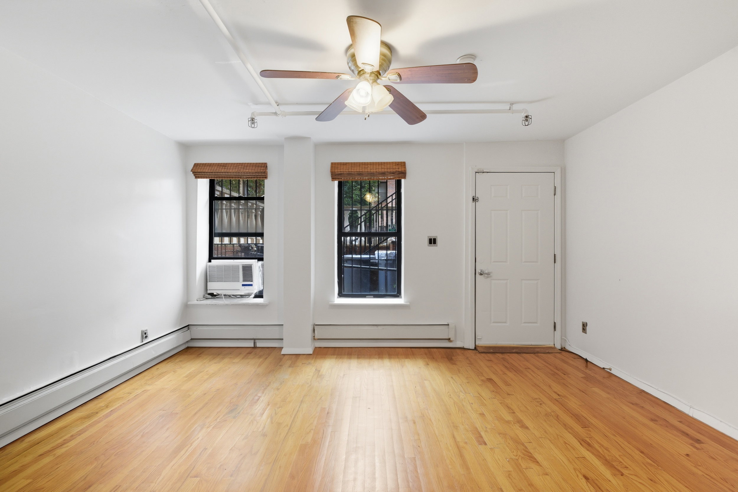 420 East 117th Street, Unit 1 Manhattan, NY 10035 - Photo 2 of 9 an empty room with wooden floor chandelier fan and windows