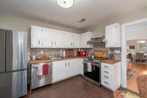 a kitchen with stainless steel appliances granite countertop white cabinets a sink a stove a refrigerator and white cabinets