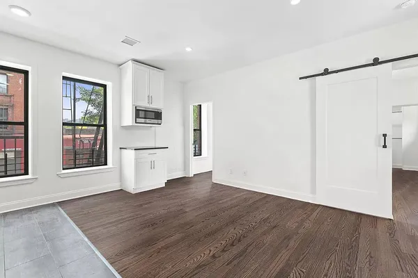 an empty room with wooden floor and a kitchen