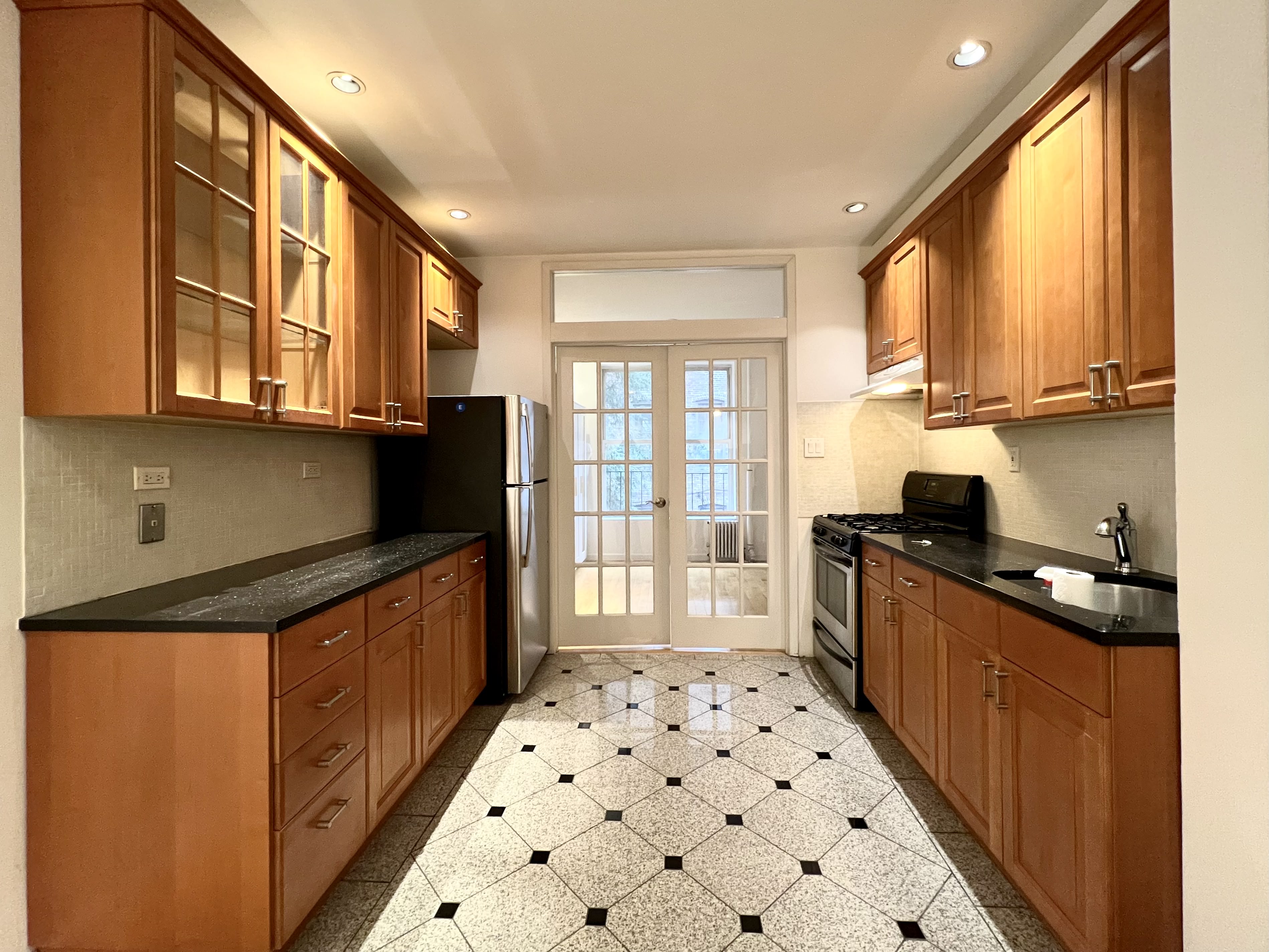 528 West 46th Street, Unit 3E Manhattan, NY 10036 - Photo 3 of 7 a kitchen with granite countertop a stove a sink and a refrigerator