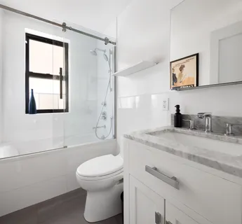a bathroom with a granite countertop sink a toilet and shower