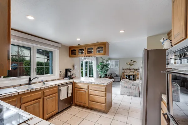a large white kitchen with a large window a sink and stainless steel appliances