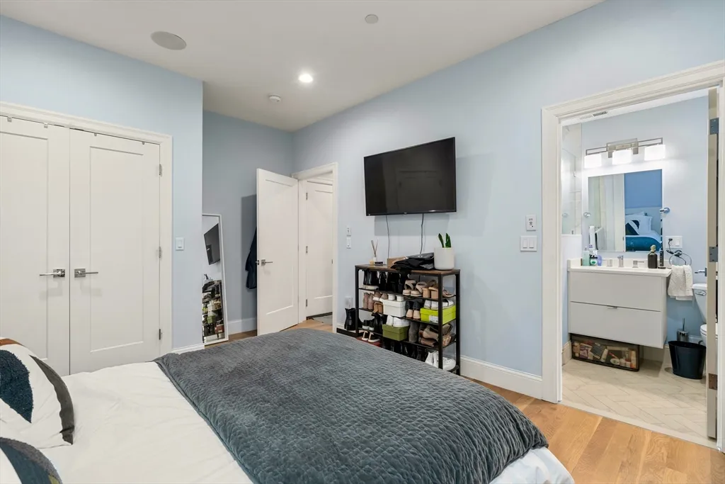 a bedroom with a bed and a flat tv screen on wall