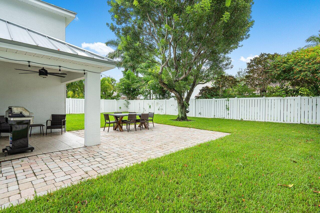 1182 Canoe Point Delray Beach, FL 33444 - Photo 31 of 46 a view of a backyard with table and chairs a barbeque and wooden fence
