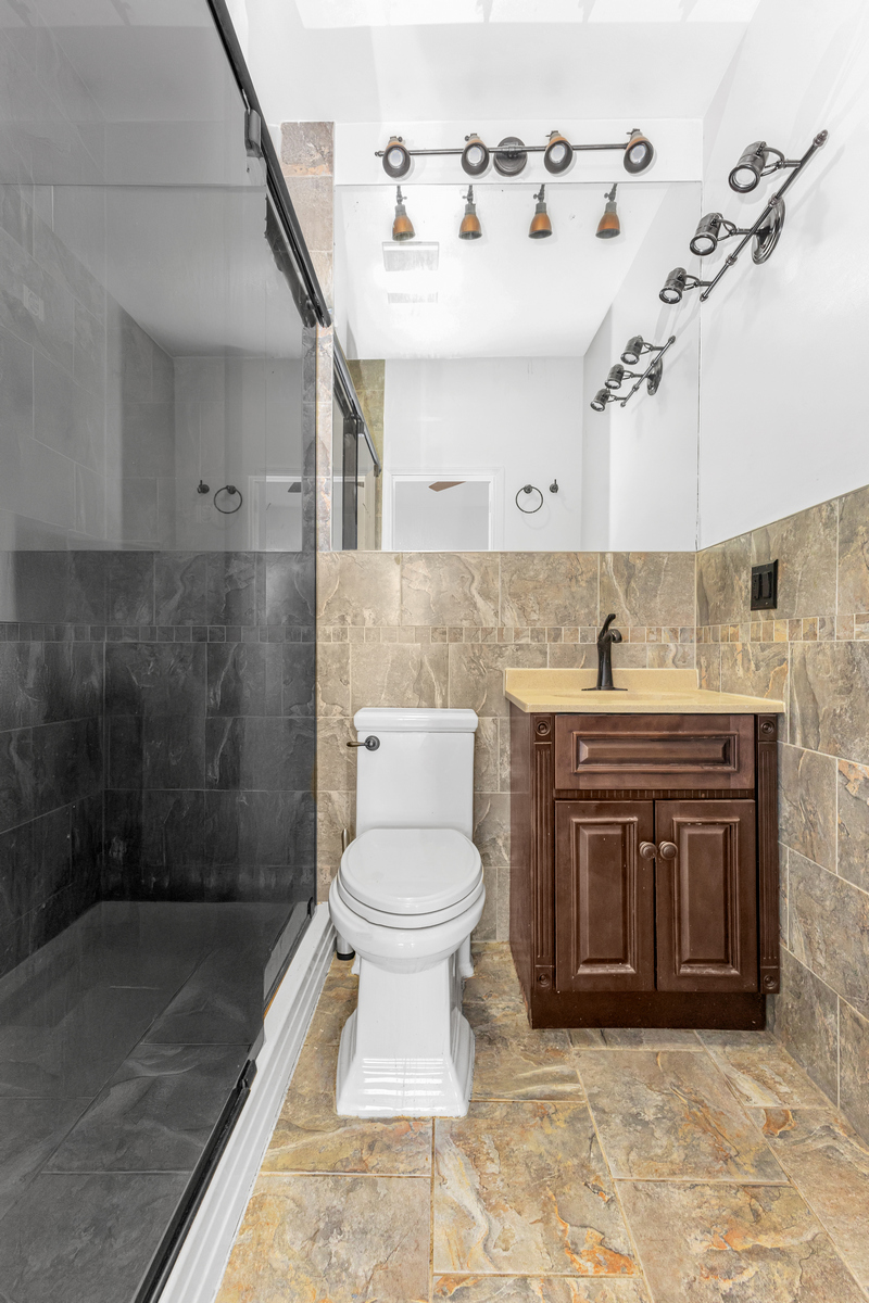 521 Dean Street, Unit 4L Brooklyn, NY 11217 - Photo 9 of 17 a bathroom with a granite countertop sink a toilet and a shower