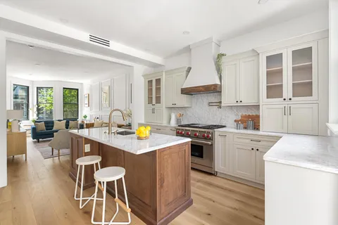 a kitchen that has a lot of cabinets in it with stainless steel appliances granite countertop a stove a sink dishwasher and white cabinets with wooden floor